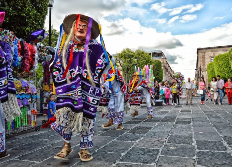 A vibrant festival procession with colorful costumes and traditional music, capturing the essence of a rich cultural celebration. This image is used on the webpage Random Language Generator.