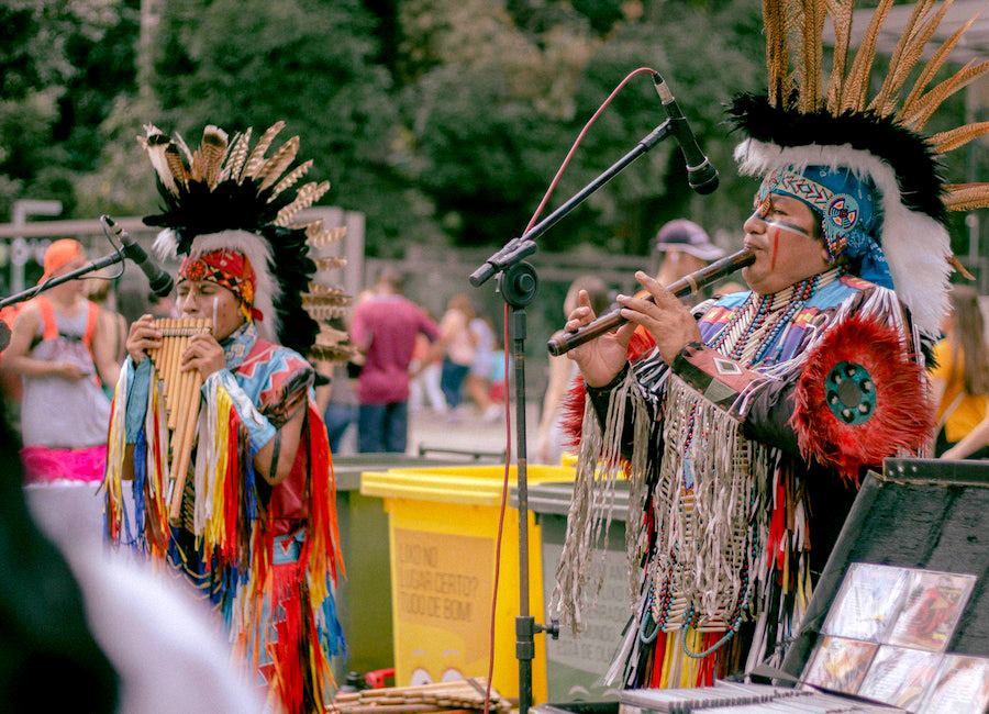 A lively procession of people in vibrant traditional attire, parading with joyful expressions and playing musical instruments, radiating the spirit of a rich cultural festival. This image is used on the webpage Random Language Generator.