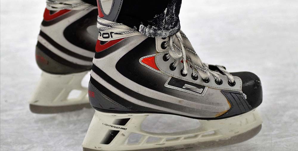 A close-up view of ice skates glistening under the rink's lights, ready for a graceful glide on the ice.