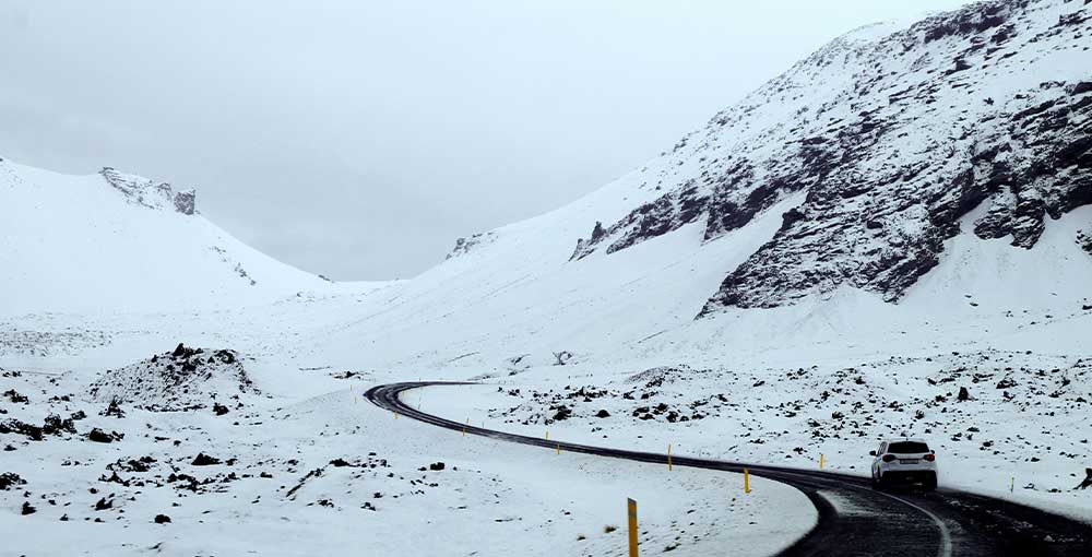 a snowy landscape in Snæfellsnes Peninsula, with a road and a car.